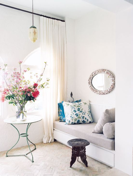 a neutral entryway with curtains, a pendant lamp, a cozy daybed, a mirror and a stool plus a stylish vintage coffee table