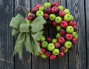 a colorful fall wreath of green and red apples and with a larrge green burlap bow is a very cool idea