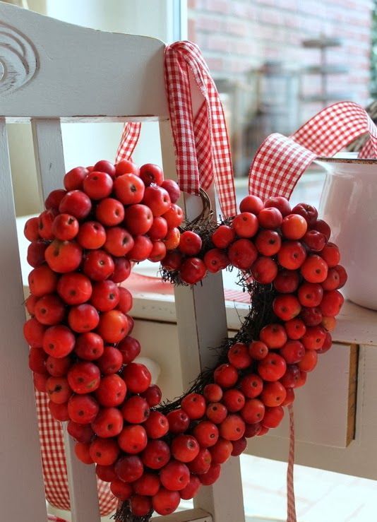 a red heart shaped wreath of faux apples and with red plaid ribbons is a cool autumnal decoration for the fall