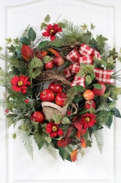 a bright and wild fall wreath of faux greenery, foliage, twigs, faux flowers and apples and red plaid ribbons