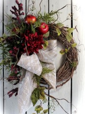 a wild fall wreath of vine with faux greenery, leaves, twigs, berries, apples and burgundy blooms plus a burlap and lace bow