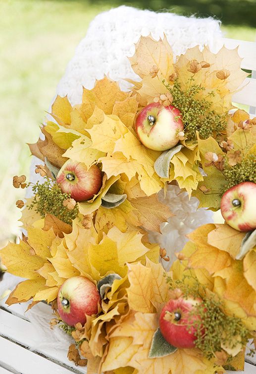 a beautiful and warm-colored fall wreath of yellow fall leaves, dried greenery and apples is soft and warm-colored