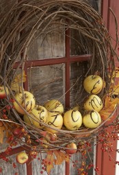 a rustic fall wreath of vine, real apples with letters, branches with berries and fall leaves is all-natural and cool