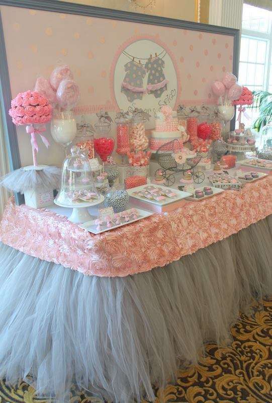 a grey and pink dessert table with tulle, fabric roses, fake floral arrangements and a polka dot backdrop