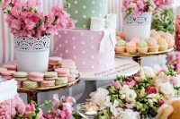 a bright pink and green baby shower with bright florla arrangements, colorful macarons and a cute two color cake with teddy bears