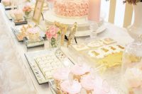 a girlish pink and gold dessert table with stripes, ruffles, candles and gold frames for a girl’s baby shower