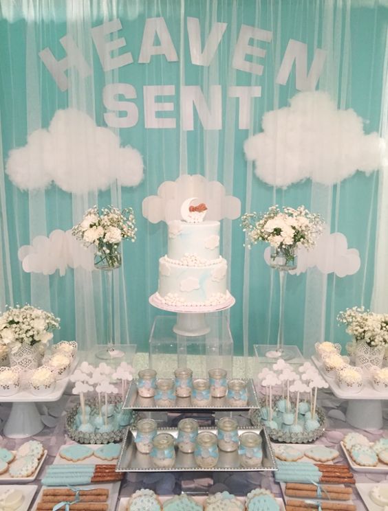 a light blue and white dessert table with clouds, neutral floral arrangements, blue and white sweets