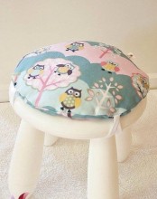 a white IKEA Mammut stool topped with a colorful pillow is very comfortable to sit on