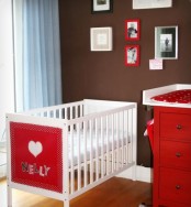 a bright chocolate brown, red and white nursery with a white IKEA Sundvik crib and a red accent on it for more fun