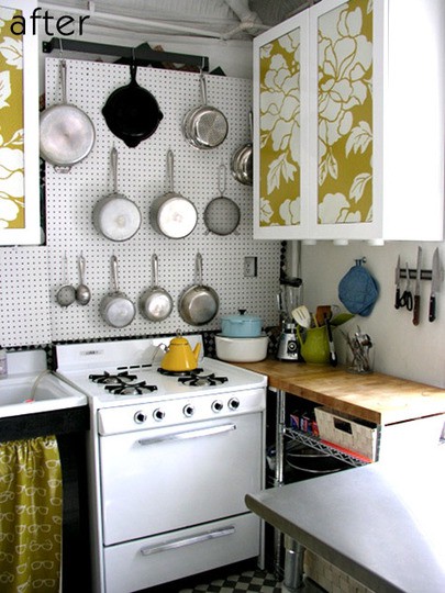 a tiny modern kitchen with floral printed cabinets, a pegboard for holding pans, a cooker and butcherblock countertops