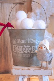 a printed galvanized bucket with snowballs and a small red bow is a lively rustic decor idea to rock