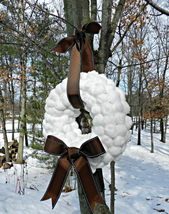 a large snowball wreath with a brown bow and a ribbon on top is a chic idea for winter