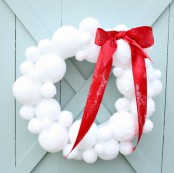 a snowball Christmas wreath accented with a large red bow will bring a snowy and fairy-tale feel to the space