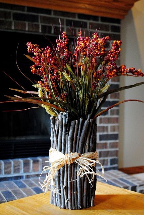 a fall decoration of greenery and berry branches and with twigs and sticks covering the bouquet looks very natural