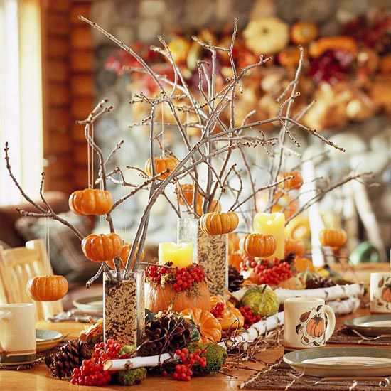 tall glasses with grain, twigs and branches with pumpkins, pinecones, faux gourds and veggies and berries compose a chic fall centerpiece