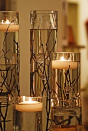 an exquisite fall decoration of tall vases with twigs and branches plus floating candles is lovely and chic