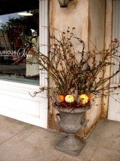 a vintage urn with branches and twigs, vine and mini pumpkins plus berries is a bold woodland decoration