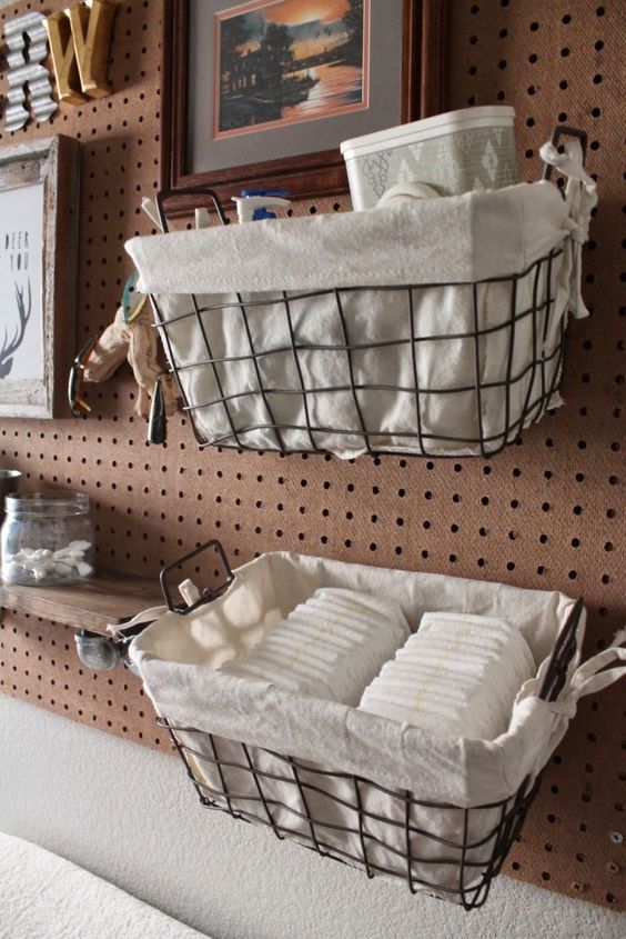 a pegboard with wire baskets covered with fabric, with artworks and monograms