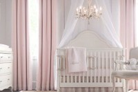 a vintage girlish nursery with vintage elegant furniture, a canopy and a crystal chandelier plus pink textiles