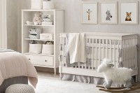 a neutral nursery with a fun gallery wall, white furniture, grey and pink bedding and a vintage chandelier