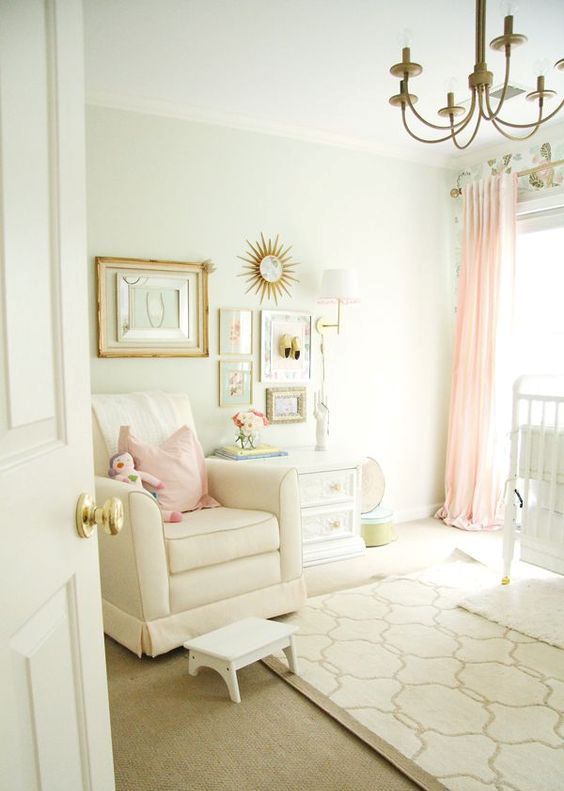 a peaceful and lovely girl's nursery done in neutrals, with touches of pink and gold, with a refined gallery wall and a vintage chandelier