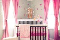 a bright girl’s nursery with grey walls, hot pink textiles, a refined chandelier with pink crystals, a butterfly mobile