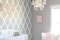 a pretty grey, white and pink nursery with white furniture, pastel bedding, a crystal chandelier and a paper butterfly mobile