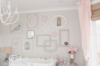 a neutral vintage nurseru with light grey walls, white and grey furniture, a gallery wall of empty frames and touches of peachy pink