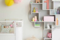 a modern colorful nursery with a color block wall, a grey shelving unit, a white crib and colorful accessories and toys