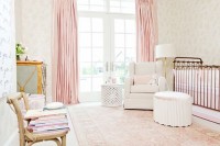 a refined glam nursery with neutral walls, blush and pink textiles, a vintage crib and a gold chandelier