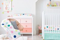 a bright and cheerful nursery with all white everything and touches of bold polka dots on the textiles, wall and cushions