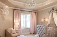 a glam pastel nursery with dove grey walls, a grey crib with a canopy, pink curtains and a crystal chandelier plus a butterfly mobile