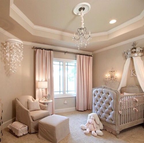 a glam pastel nursery with dove grey walls, a grey crib with a canopy, pink curtains and a crystal chandelier plus a butterfly mobile