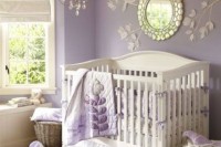 a vintage lilac and white girl’s nursery with lilac walls, a branch art wiht a mirror, a crystal chandelier and white furniture plus lilac textiles