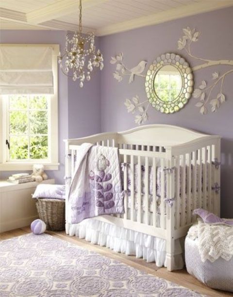 a vintage lilac and white girl's nursery with lilac walls, a branch art wiht a mirror, a crystal chandelier and white furniture plus lilac textiles