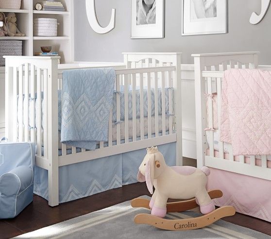 a grey and white shared nursery with white furniture, white monograms and artworks and pink and blue bedding