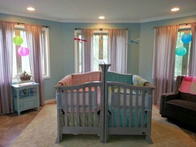 a colorful shared nursery with bright linens and lamps, with grey and blue furniture for fun