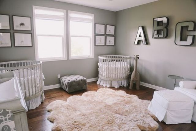 a gender neutral shared nursery with grey walls, white furniture, two gallery walls, matching cribs and monograms on the wall