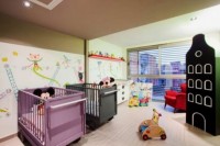 a colorful shared nursery with bright images on the wall, lots of toys and matching colorful beds is a fun idea