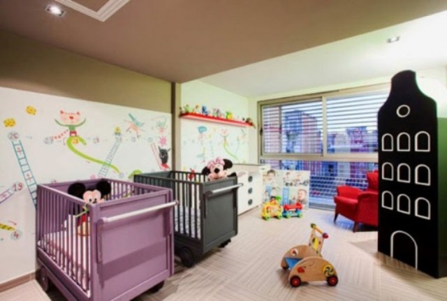 a colorful shared nursery with bright images on the wall, lots of toys and matching colorful beds is a fun idea