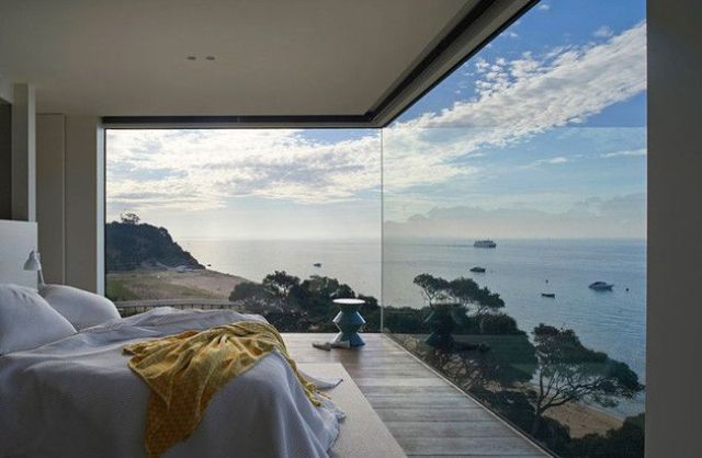 a contemporary bedroom with just some furniture and a fantastic sea view through glazed walls is a gorgeous space to stay in