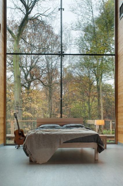 a simple and peaceful bedroom with simple mid century modern furniture and a glass wall of double height is a lovely and calming space to stay in