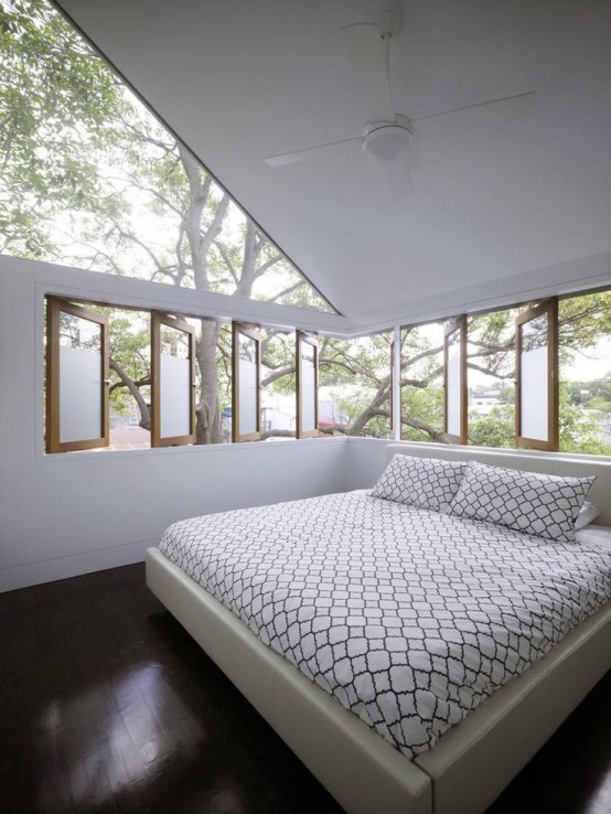 a peaceful and cozy bedroom with an upholstered bed and a gallery of windows plus a large skylight to maximize the daylight and enjoy fresh air