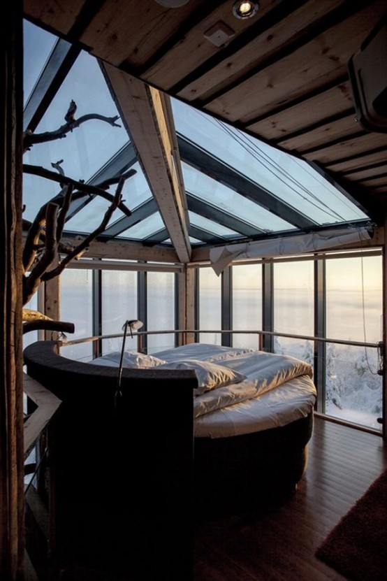 a relaxing and simple bedroom with a rounded bed, a glass ceiling and walls with a gorgeous winter view is amazing and very relaxing