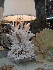 a seaside table lamp with corals at the base and a neutral lampshade is a lovely decoration for a coastal interior