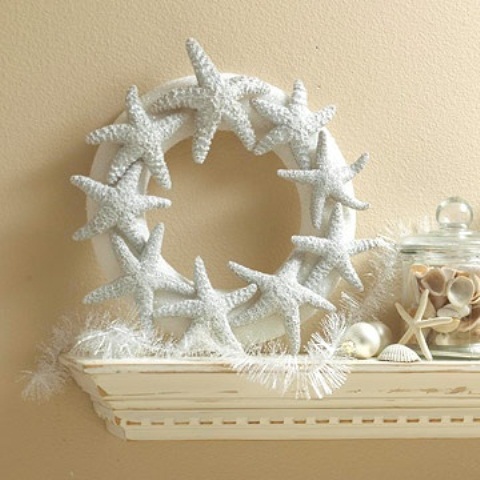 a beach mantel with a starfish wreath, a jar with seashells and starfish plus a feather garland