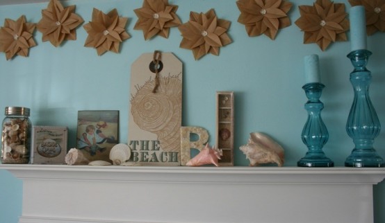 a beach mantel with seashells of various shades, artworks and blue candles in blue candleholders