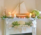a refined beach mantel with candles, green and white hydrangeas, a large boat, a burlap garland and greenery and white flowers