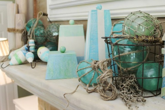 a beach mantel with blue glass floats, colorful striped floats and creative striped candles in pyramide shapes
