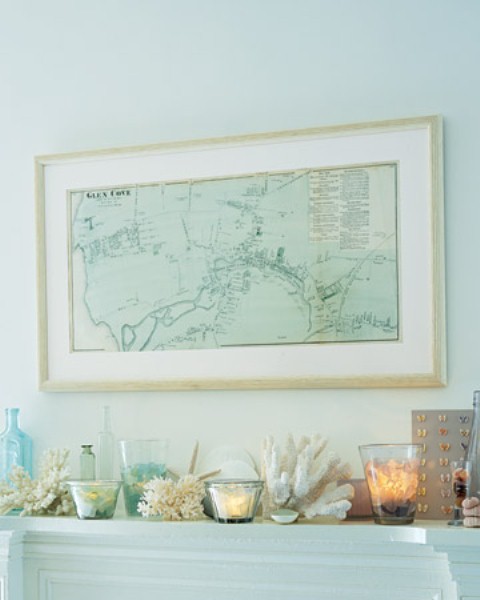 a beach mantel with corals, starfish, bottles in blue and candle holders of glass